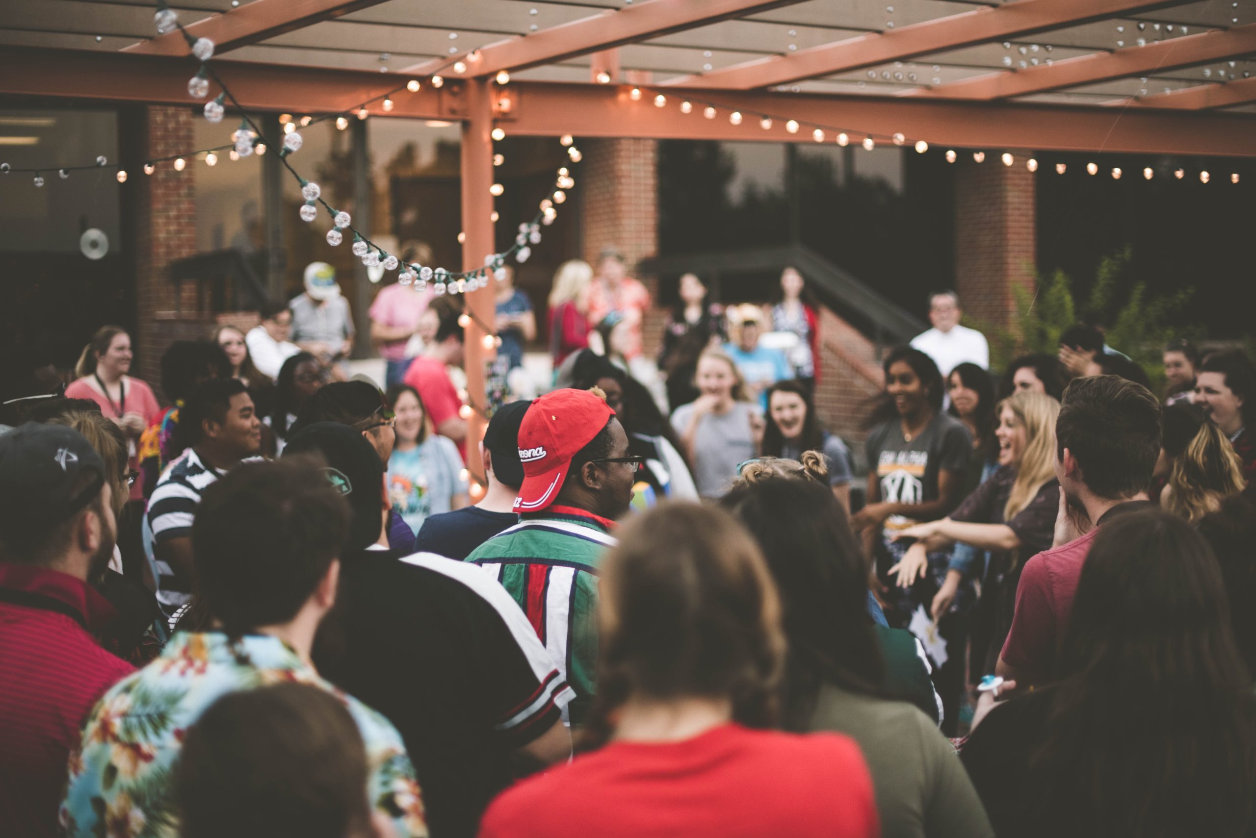 Crowd of people standing under a pergola with lights