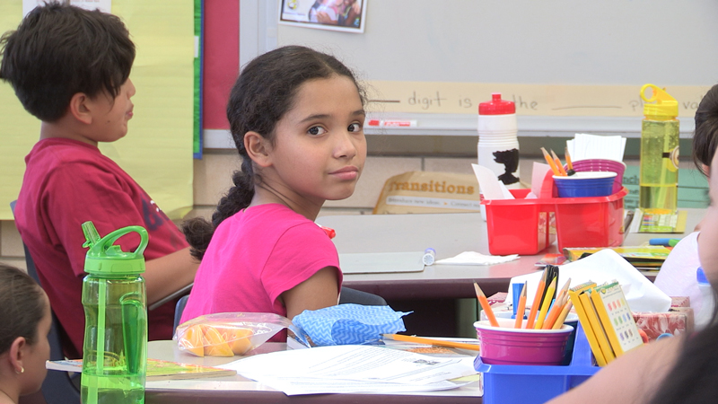 Image of an elementary school girl in a classroom, looking at the camera.