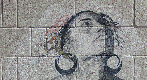 A concrete block wall with an image wheat pasted to it of a woman looking towards the sky