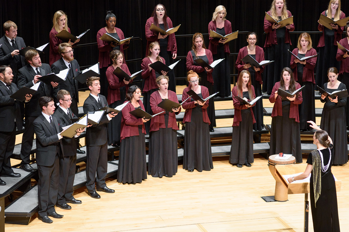 Choral conductor on stage leading MSU Denver Chorale in a performance