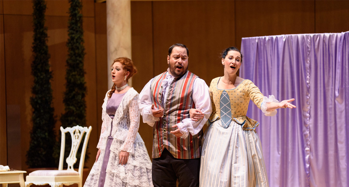 Three opera singers on stage performing Figaro in period costume