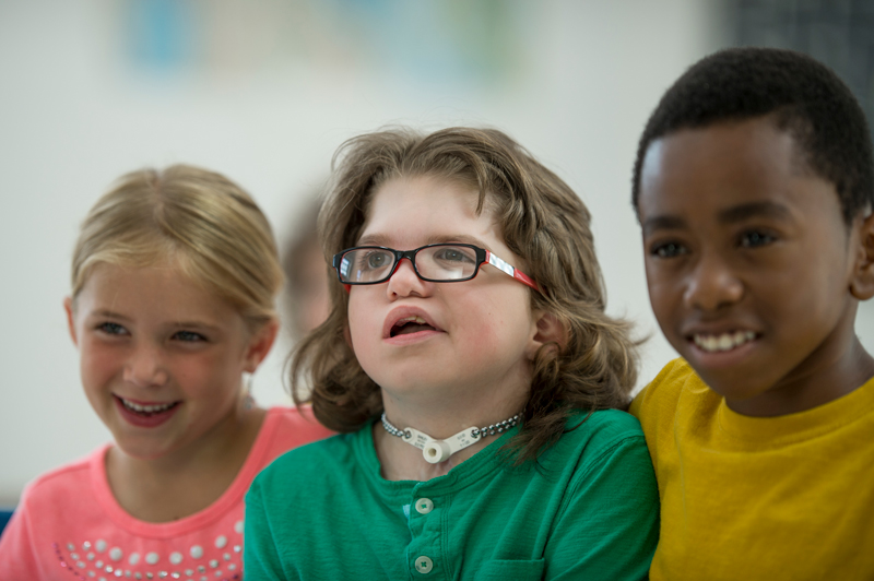 Image of three young children sitting together smiling.