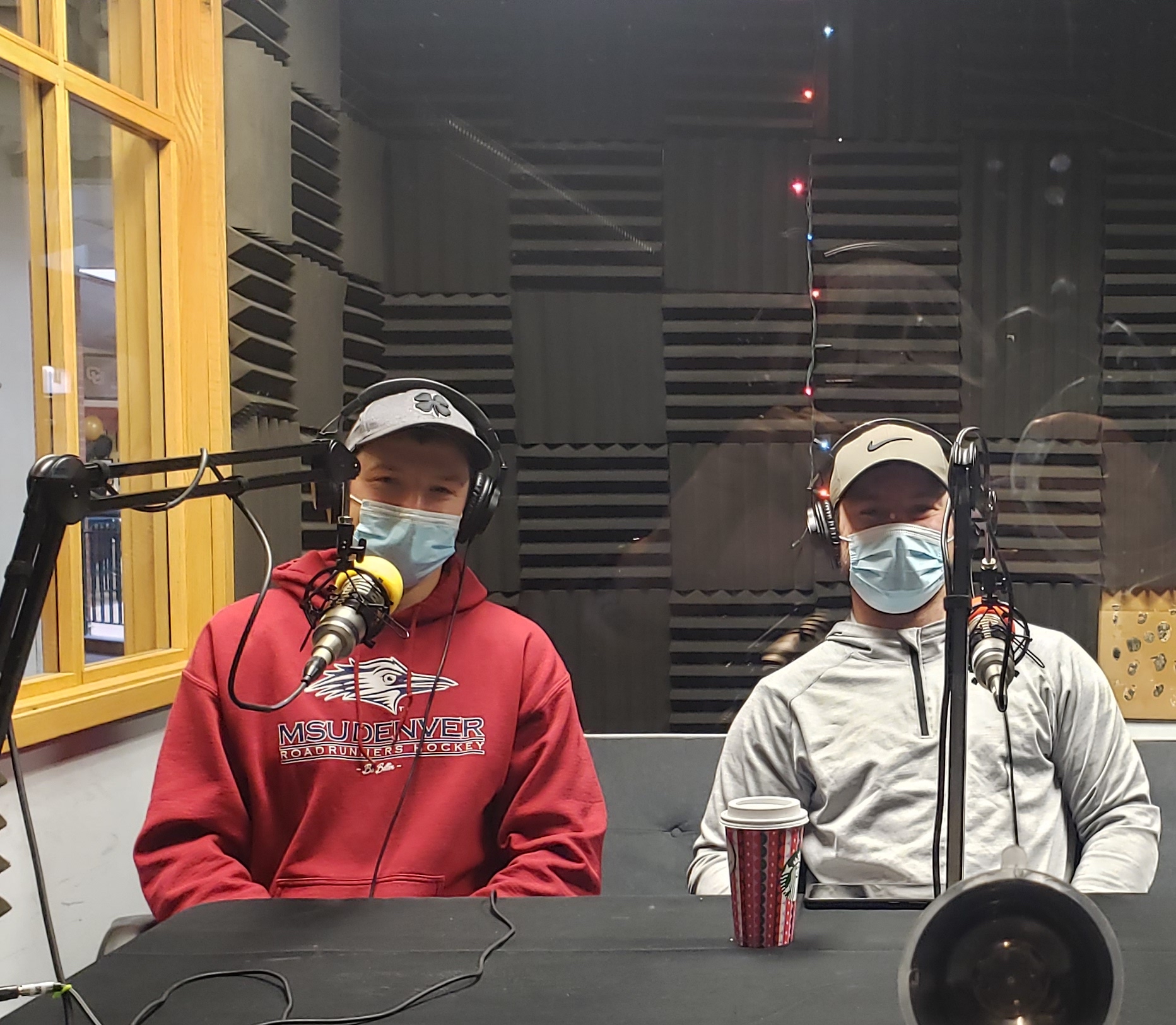 The President and Vice President of the Club Hockey team sitting in the podcast booth with headphones on