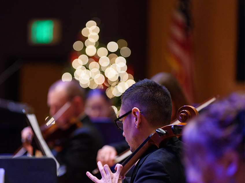 Cellist performing in front of twinkle lights