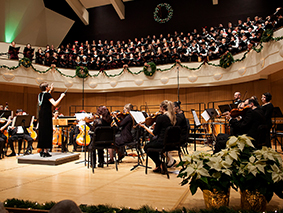 MSU Denver Festival Choir and Symphony performing on stage with white poinsettias