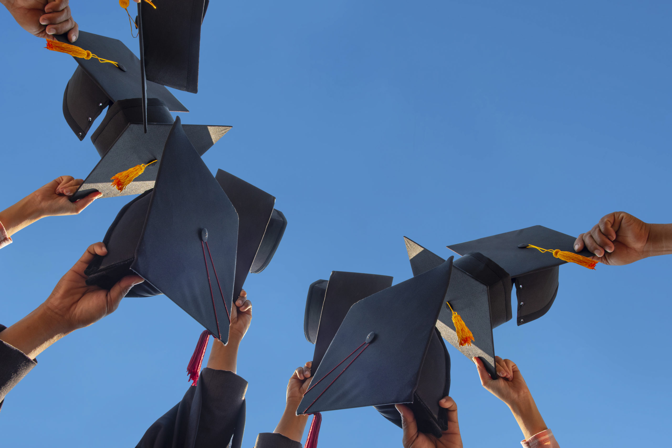 The students holding a shot of graduation cap by their hand in a bright sky during ceremony success graduates at the University, Concept of Successful Education in Hight School,Congratulated Degree