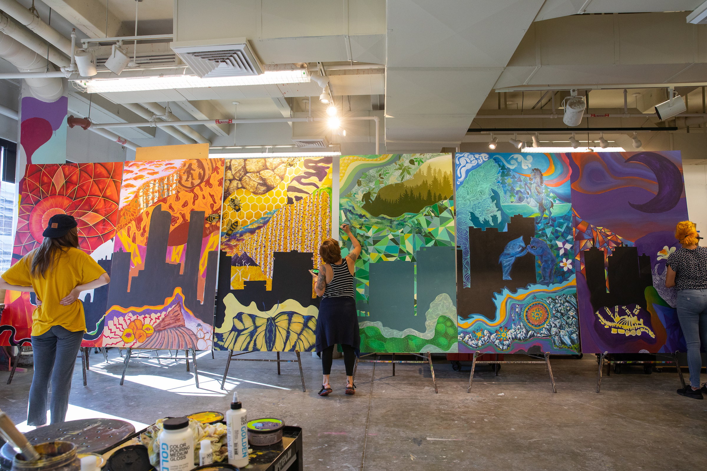 3 students painting a multicolored mural