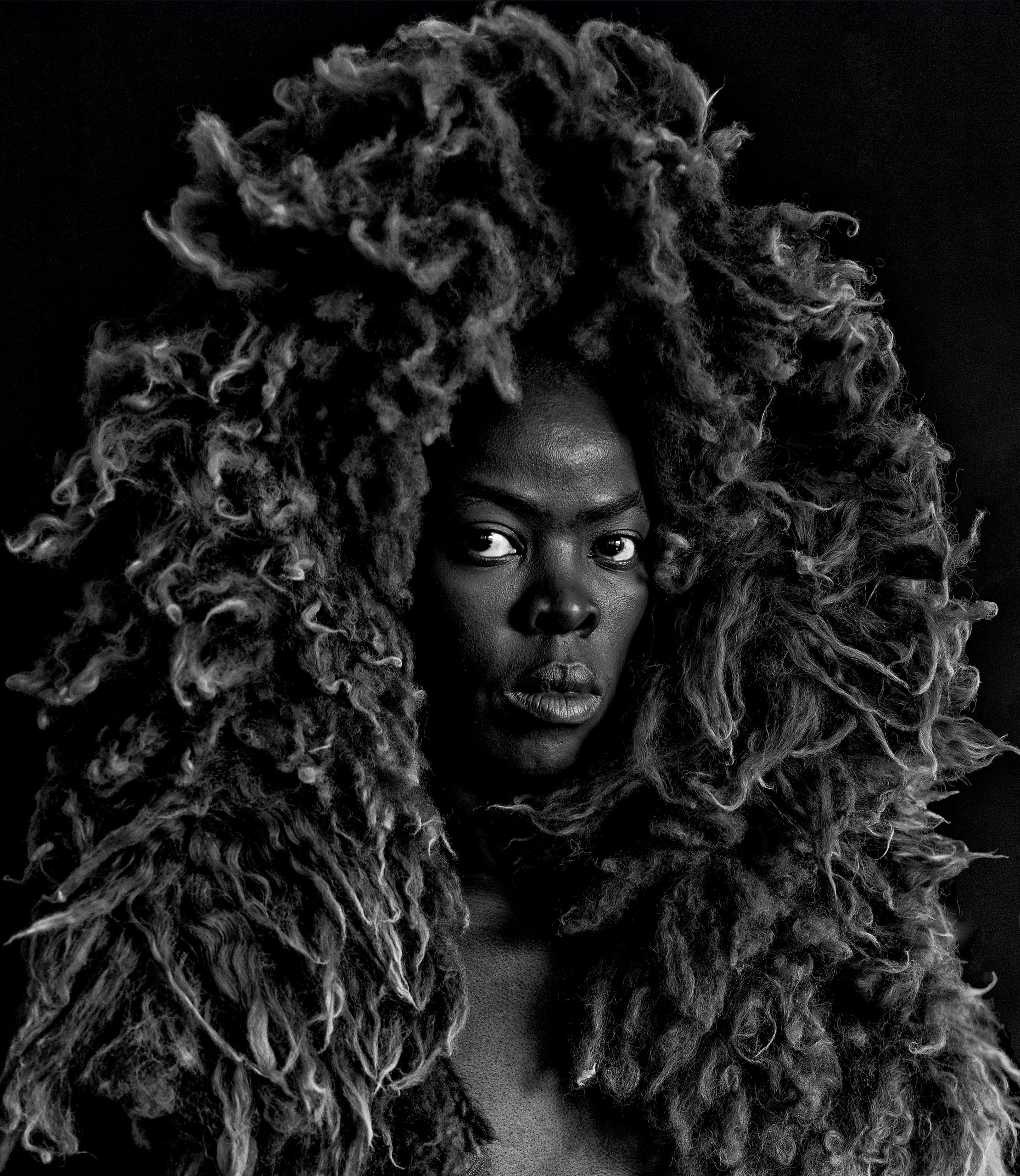Black and white portrait of a person with a large, textured mane encircling their face.