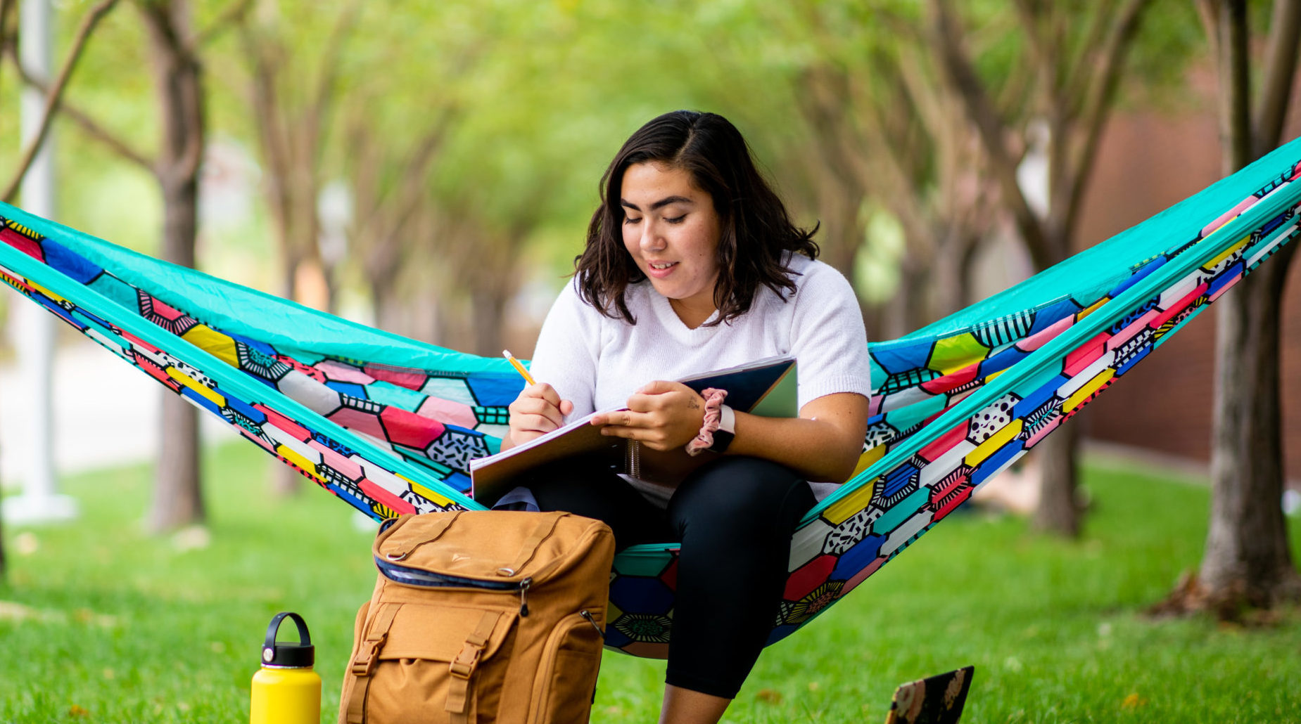 Student sitting in hamock outside on campus studying