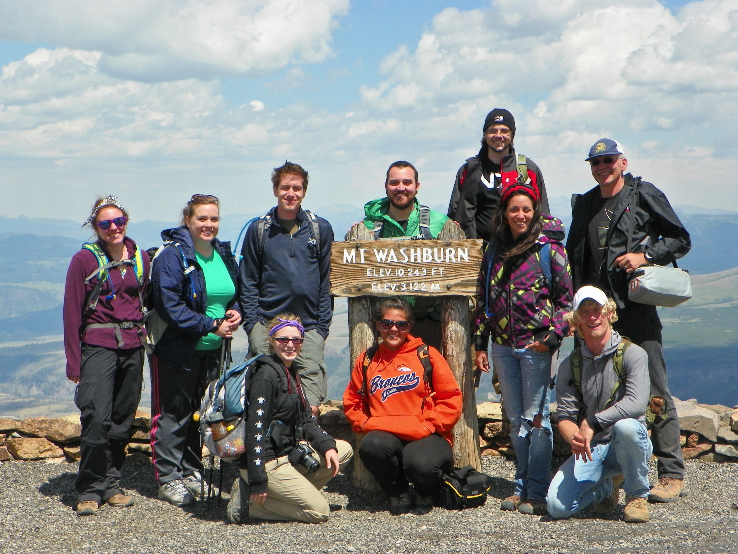 ten hikers posing with Mt. Washburn summit sign