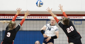 Volleyball star Rylee Hladky hits the ball over the net and two defenders