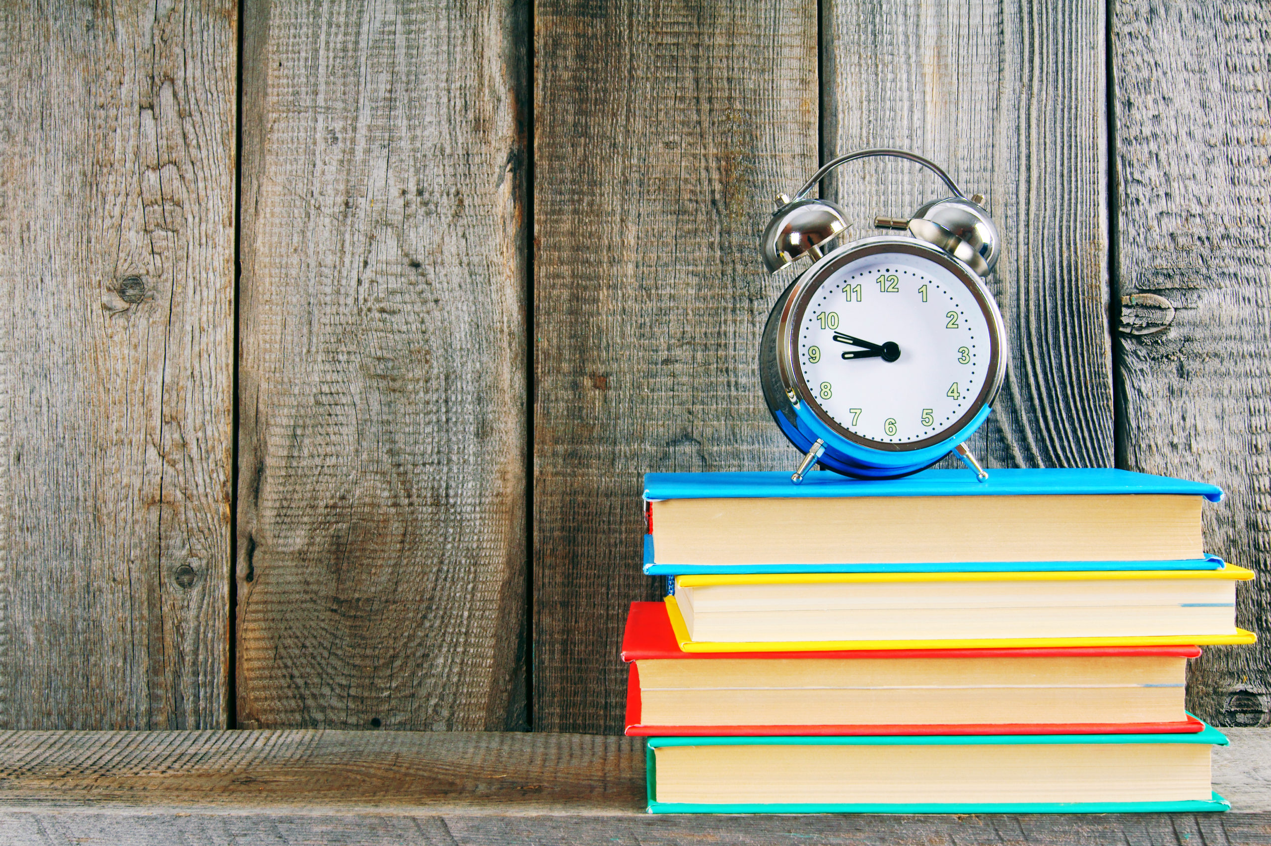 An alarm clock sitting on top of a brightly colored stack of books
