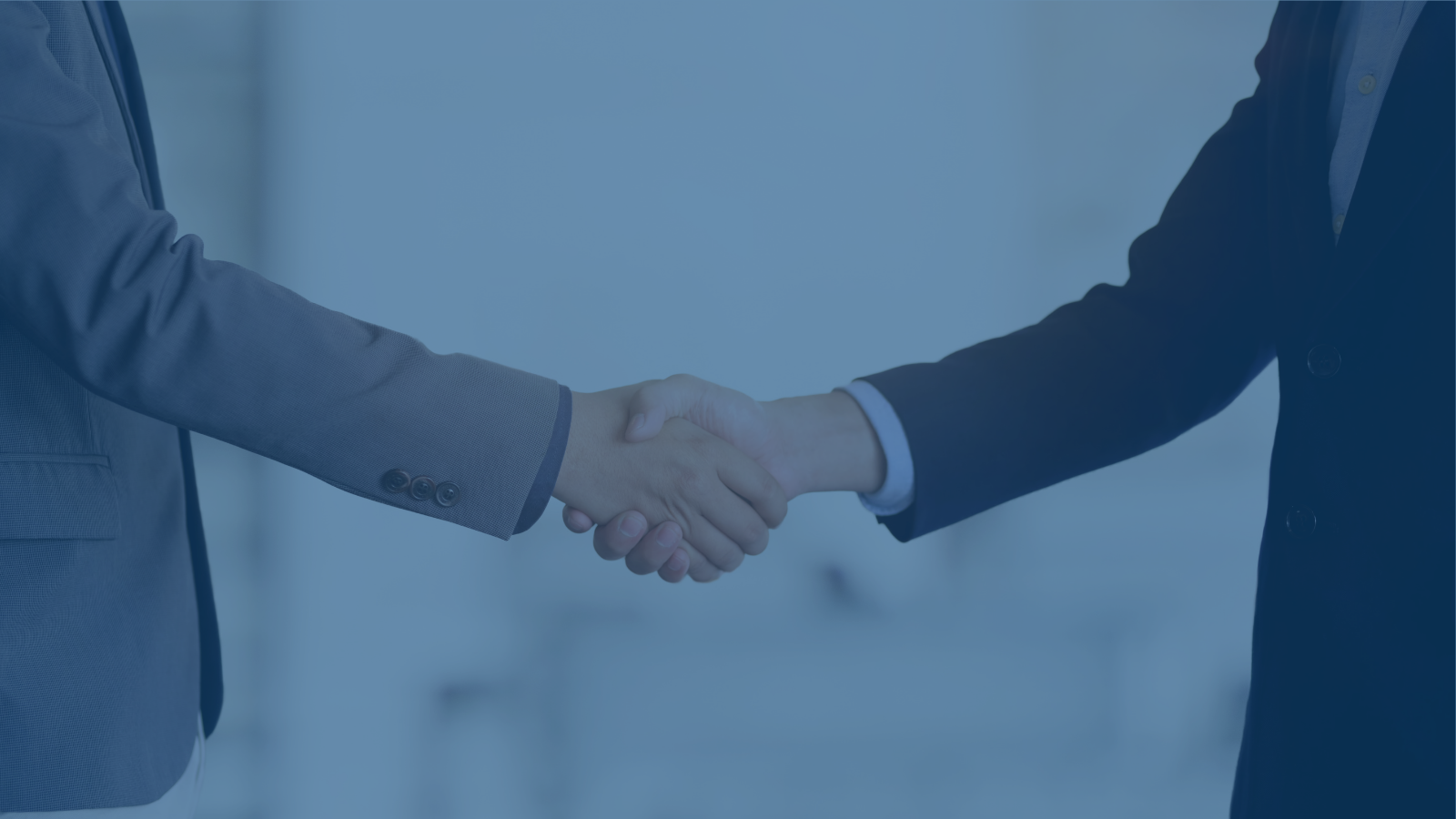 A blue filtered close up of two business men shaking hands.