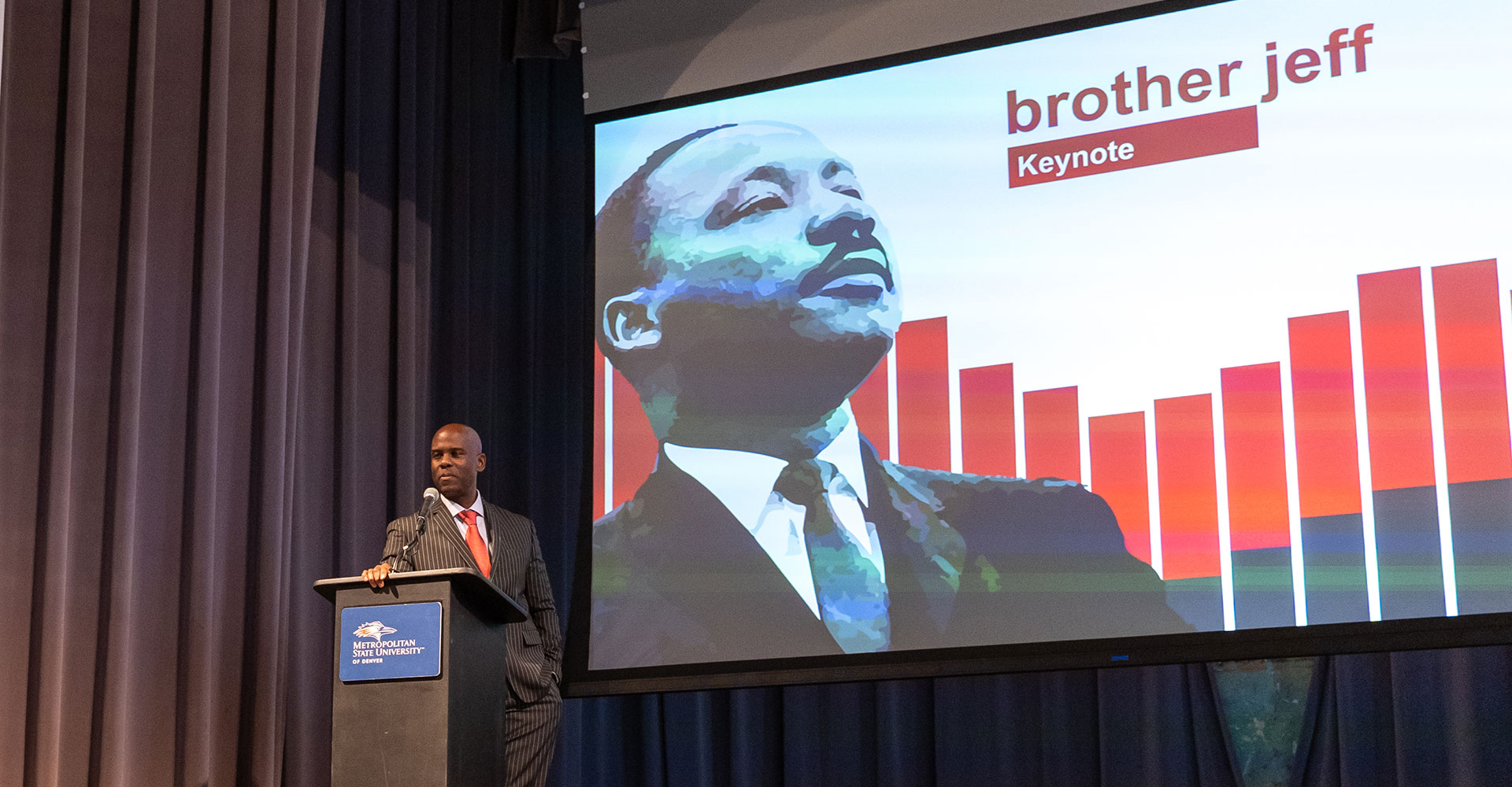 Jeff Fard, aka brother jeff, at an MSU Denver podium with a photo of Dr. King on a slide behind him