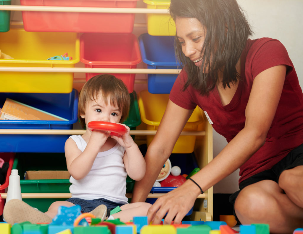 Adult woman and child play together on colorful toys background.