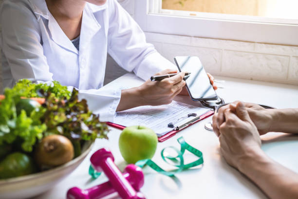 Nutritionist giving consultation to patient with healthy fruit and vegetables