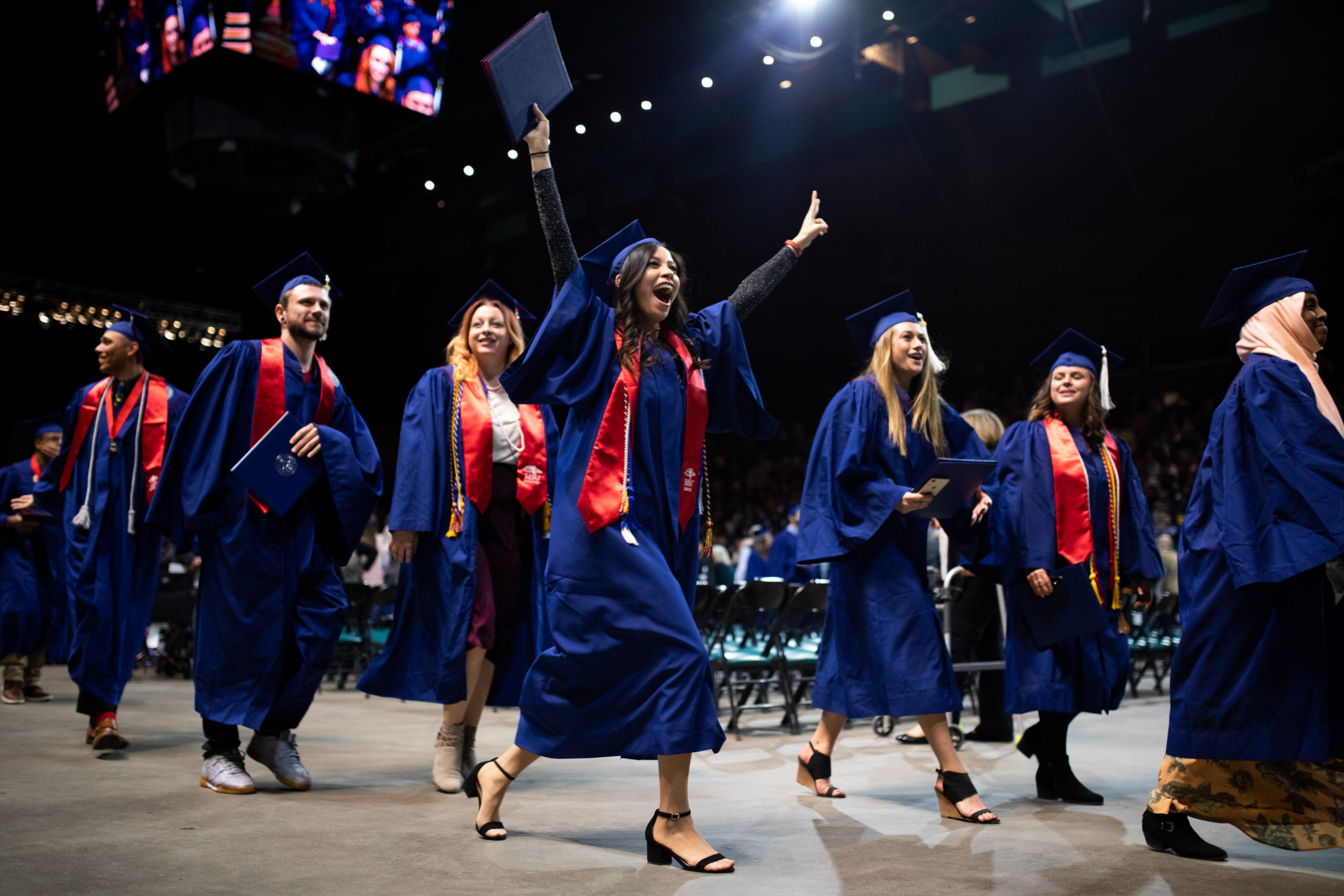 student celebrating with her hands in the air at graduation