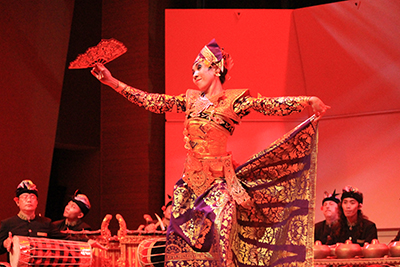 Indonesian dancer performing in front of gamelan instruments