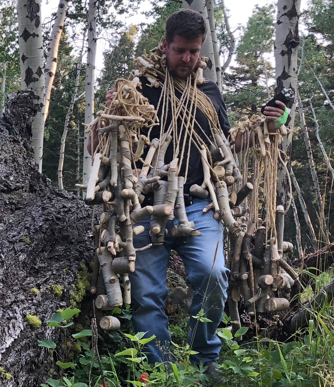 Professor Marin Abell surrounded by wooden sculpture almost looking like he is wearing it as a costume.