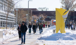 Students walking through a snowy campus on the sidewalk