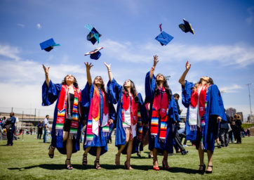 five women throwing their caps in the air at graduation