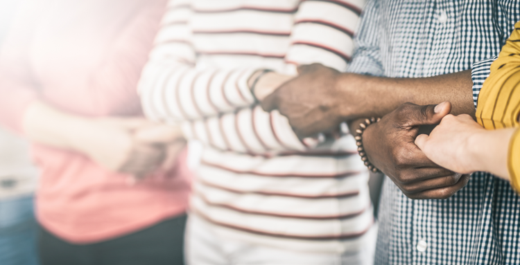 Four people standing in a line arms crossed holding hands