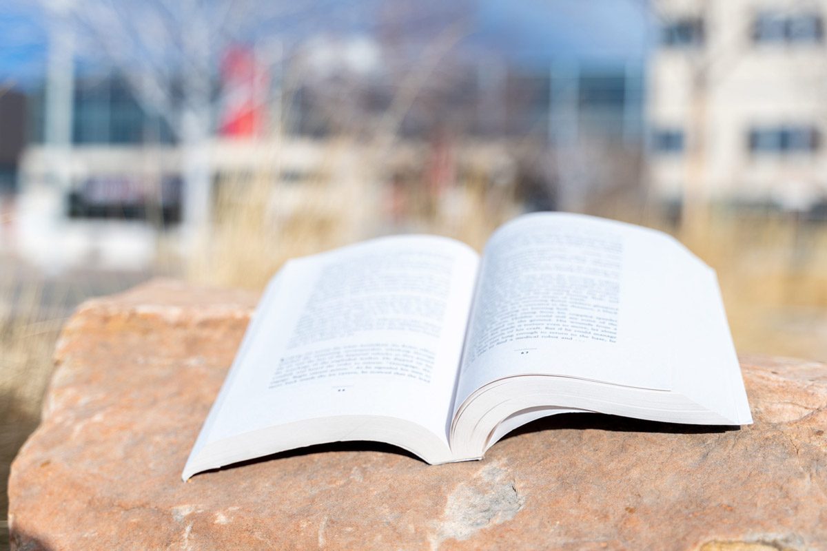 open book sitting on a rock on campus