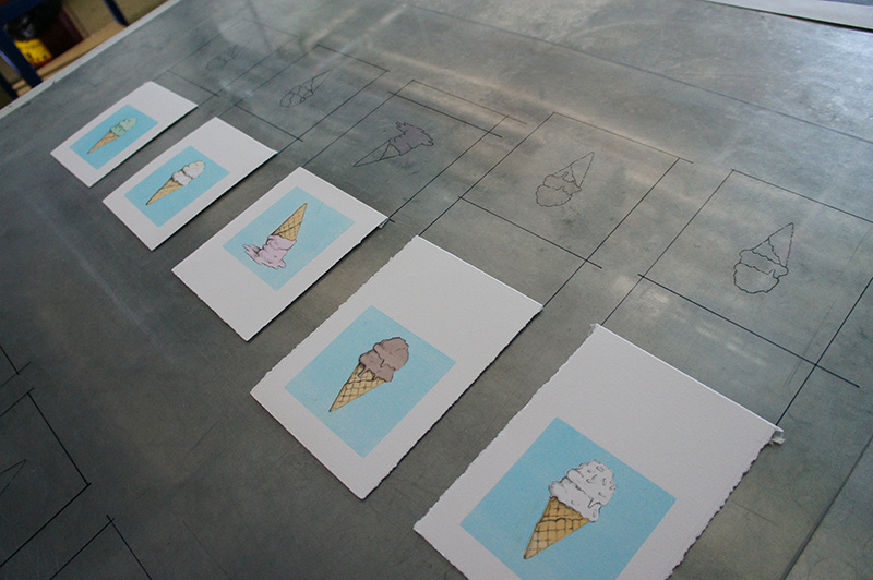 Five illustrated ice cream cone prints on a gray surface with sketched outlines in the background.