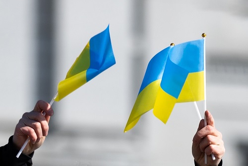 Close up of two hands waiving Ukraine flags.