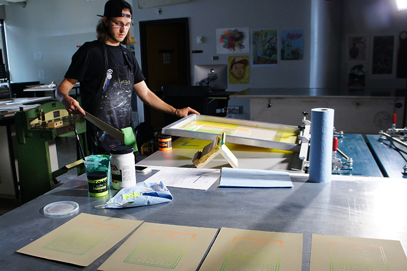 Person working on a screen printing project in an art studio.