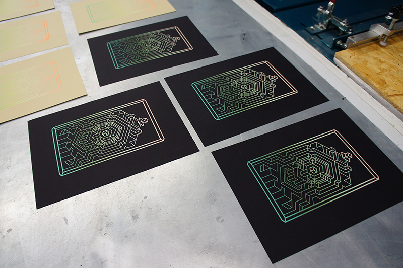 Black sheets with iridescent geometric designs on a metal surface.