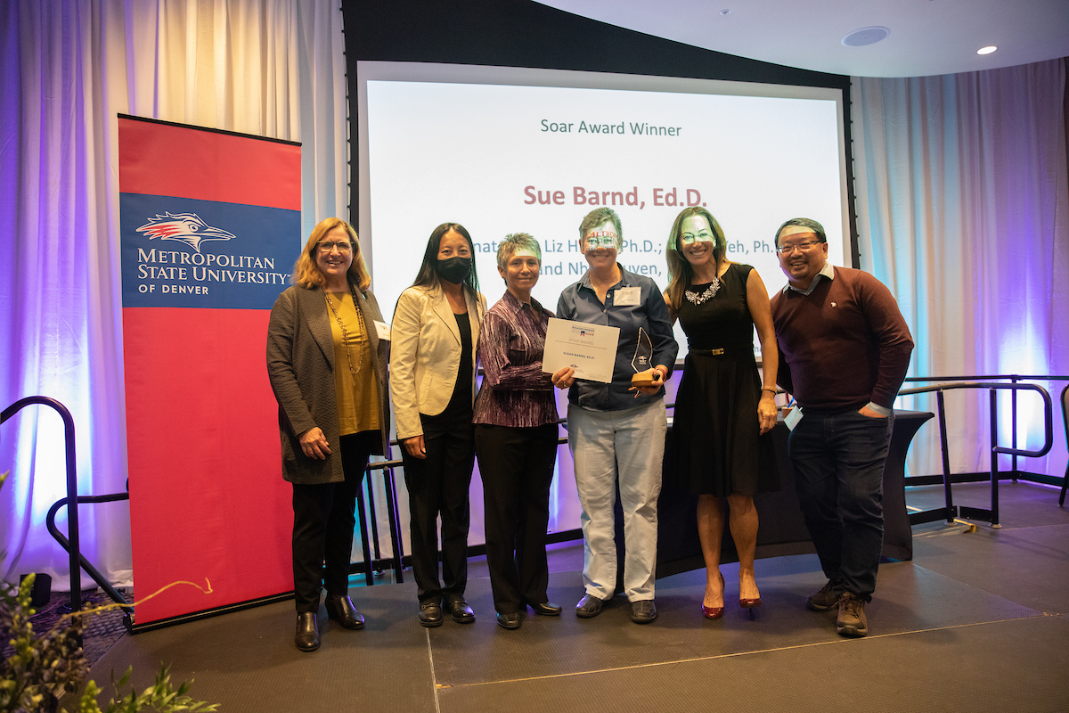 Soar Award winner Sue Barnd, Ed.D., poses with award, family members and colleagues at 2021 Roadrunners Who Soar awards ceremony.