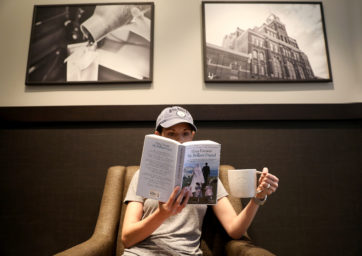person reading a book and holding a cup of coffee