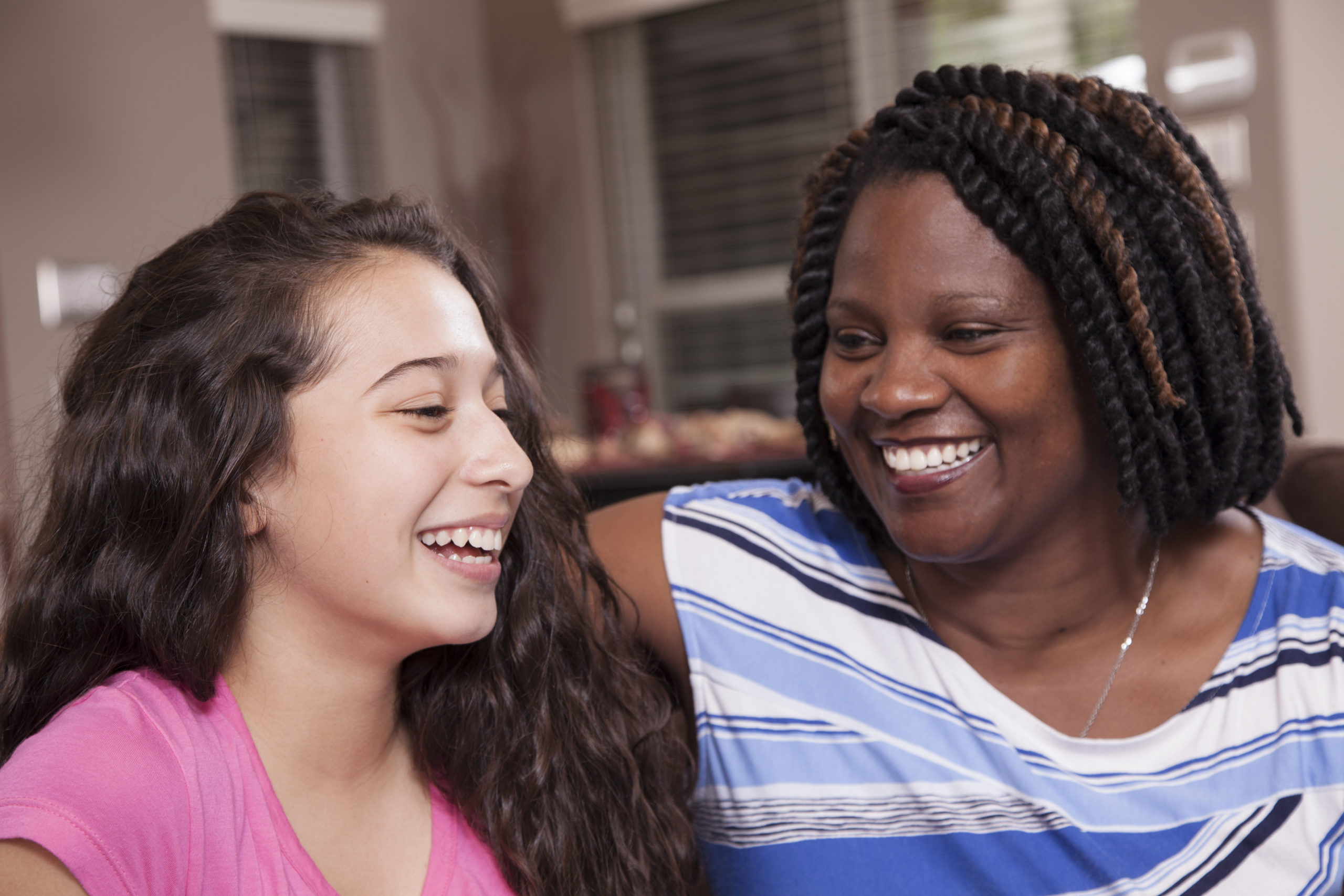 Multi-ethnic family.  Teenage girls and mom at home.  Hugs.