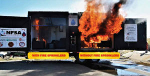 Training demonstration of a controlled fire within a mobile home. The left side features a small fire labeled "with fire sprinklers" while the right shows a large fire labeled "without fire sprinklers."