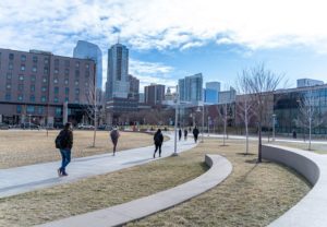 Students walking across campus in early spring; downtown Denver in background.