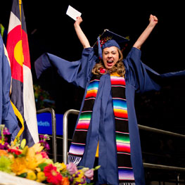 A graduate cheering as they cross the stage at commencement
