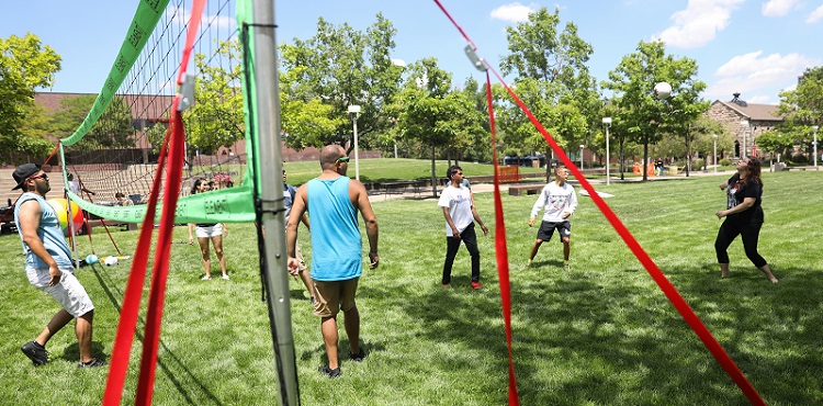 A group of students playing volleyball on the lawn near the Plaza Building on the Auraria Campus.