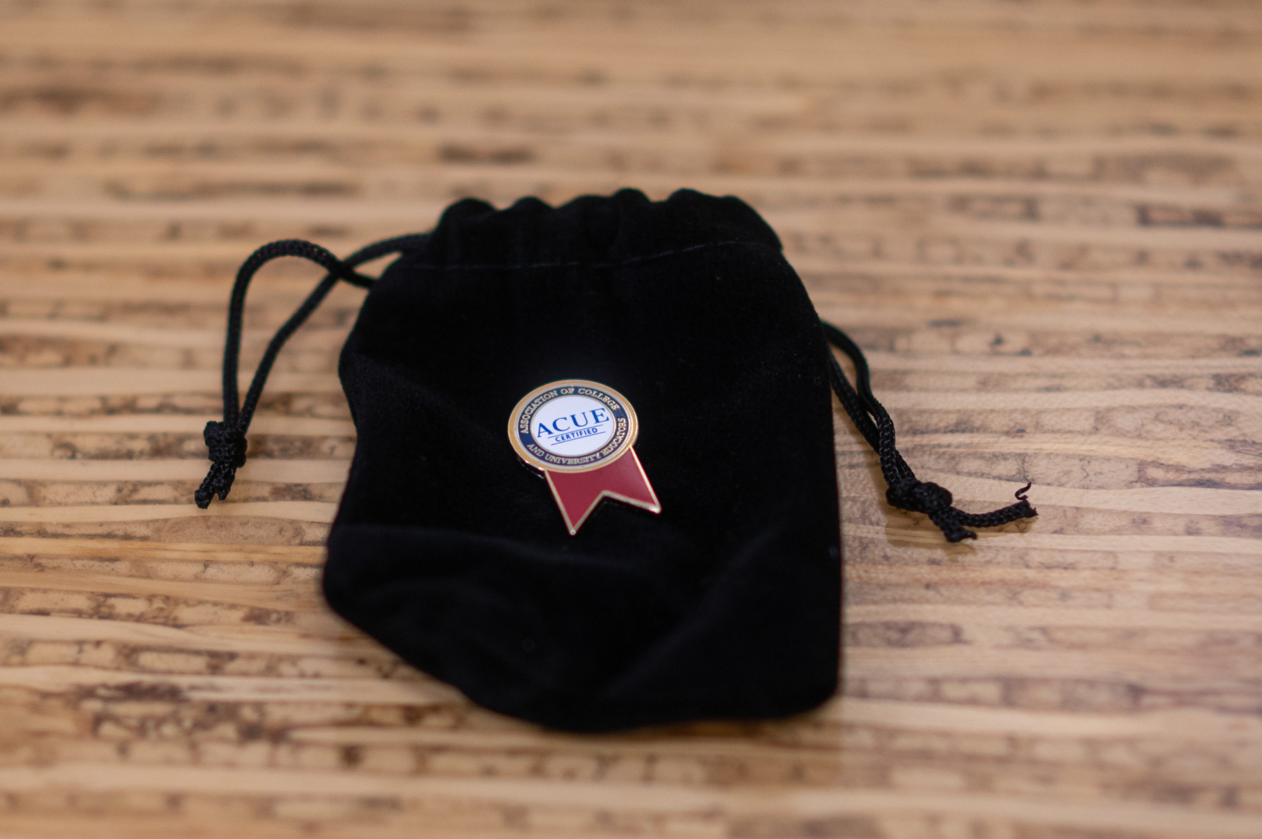 ACUE enamel pin on black velvet draw sting pouch