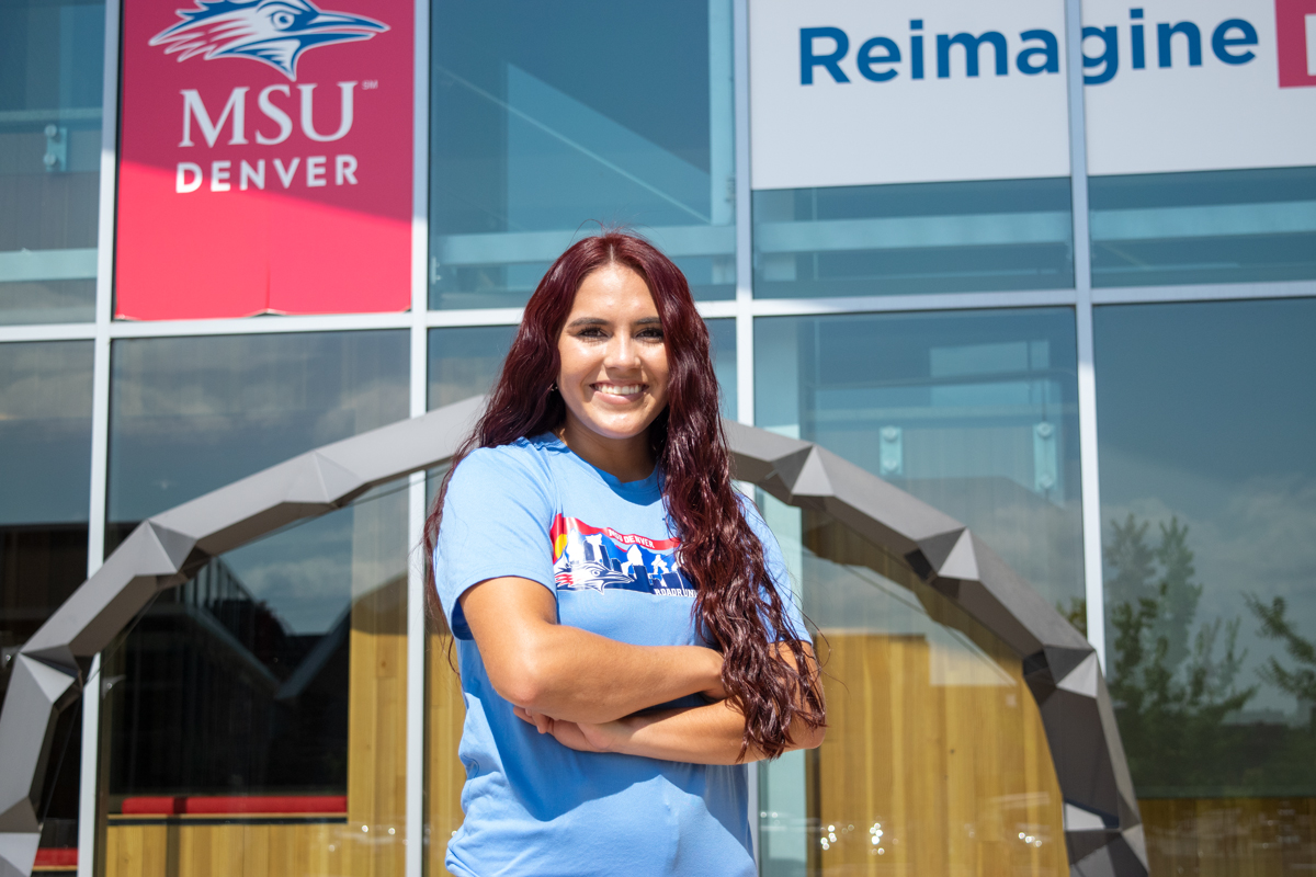 Arianna Valdez standing in front of the Student Success Building with blue windows in the background.