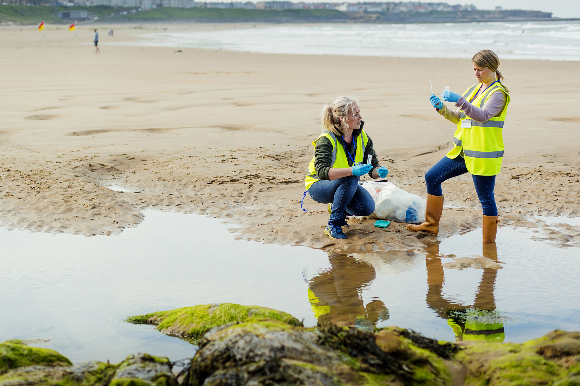 Two women wearing protective gear testing water on a beach