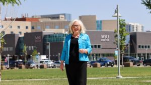 Barb Grogan standing near the Tivoli with the SpringHill Suites in the background