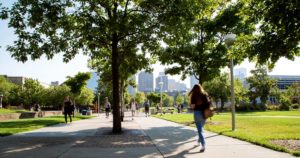 Students walking down sidewalk under leafy trees on Auraria Campus.