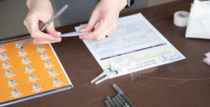 Close-up of hands filling out Covid-19 vaccination paperwork.