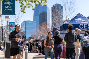 Students walking on Auraria campus next to an MSU Denver sign and info stand.