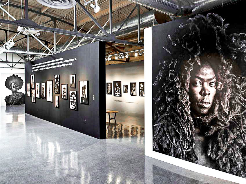 Art gallery with monochrome portraits and industrial-style ceiling.
