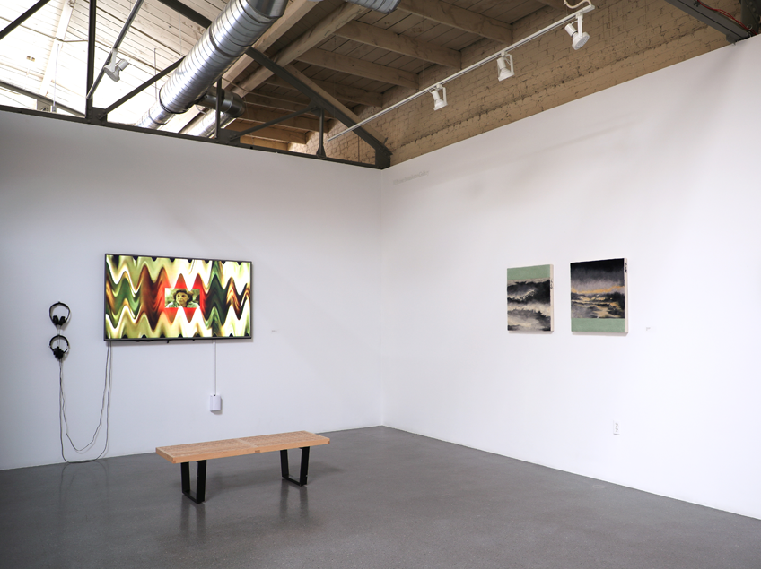 Art gallery with digital and traditional artworks on display, featuring a bench and minimalist decor.