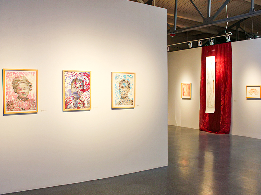 Art gallery with colorful abstract portraits and other artworks displayed on white walls.