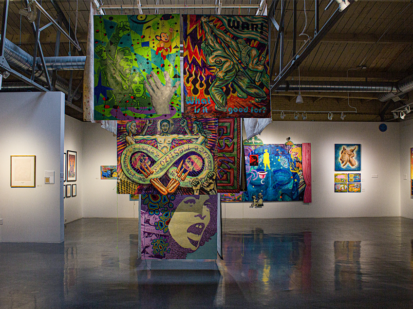 Colorful art gallery with large hanging paintings and wall displays.