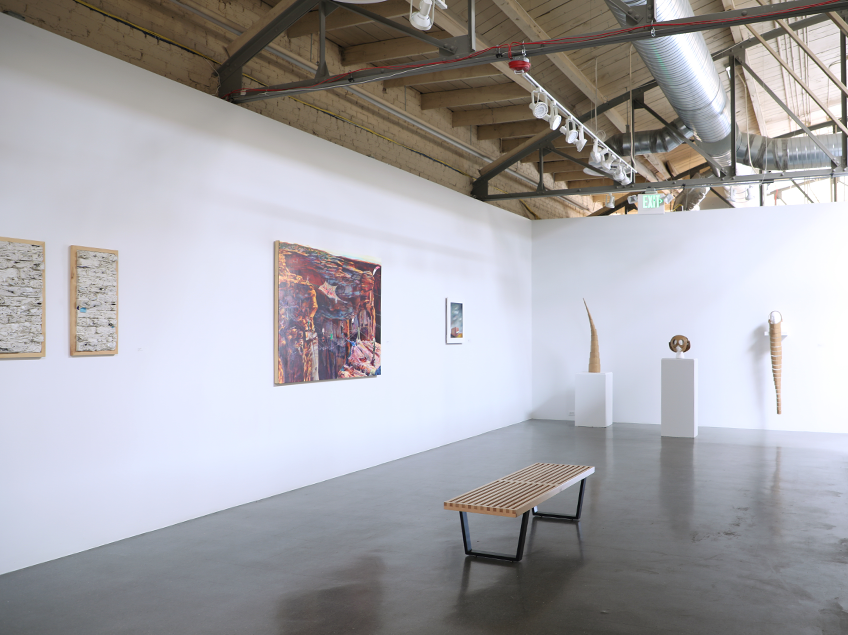 Art gallery interior with paintings, sculptures, and a wooden bench.